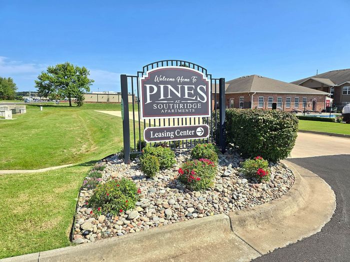 Welcoming entrance to Pines at Southridge Apartments with vibrant landscaping and clear signage pointing to the leasing center.