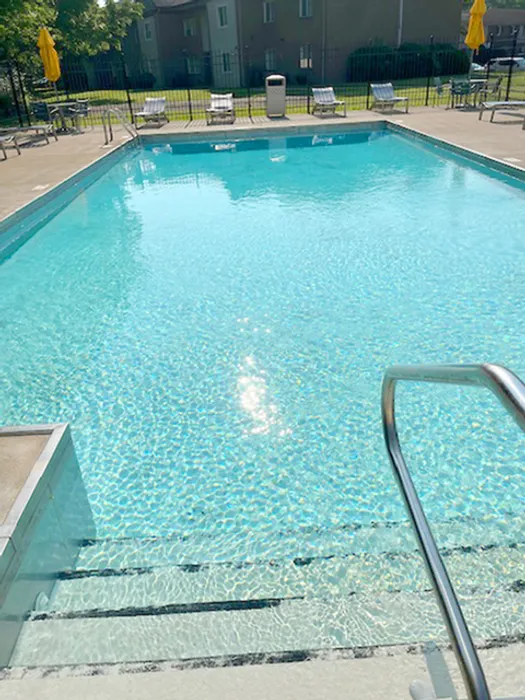 Inviting outdoor swimming pool with sparkling blue water, surrounded by sun loungers and vibrant yellow umbrellas, offering a perfect relaxation spot.