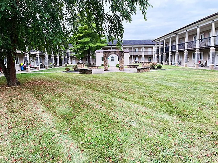 Charming courtyard view of a modern apartment complex with beautifully manicured lawns and elegant stone arches.