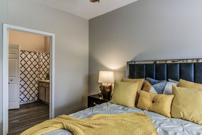 Cozy bedroom with plush pillows, soft lighting, and adjacent modern bathroom with stylish shower curtain.