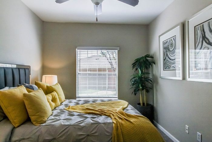 Bright and cozy bedroom with elegant decor, featuring a plush bed adorned with vibrant yellow accents and soft lighting, creating a warm and inviting atmosphere.