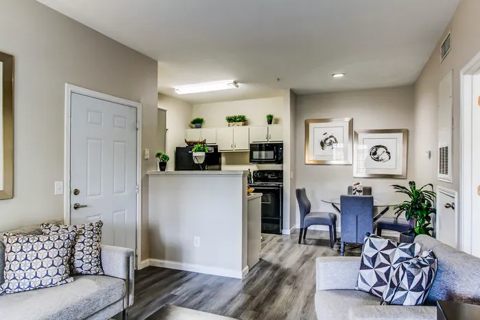 Chic and cozy living room with neutral tones, modern artwork, and an inviting dining area adjacent to a well-equipped kitchen.