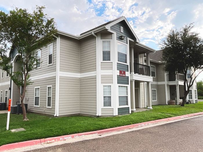 Charming modern apartment building with elegant architecture and lush green surroundings, offering an inviting and spacious residential experience.