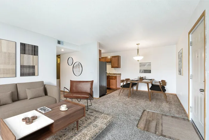 Inviting living and dining area with modern decor, plush carpeting, and an elegant chandelier, perfect for comfort and style.