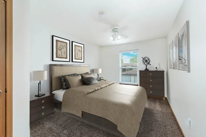 Elegant bedroom with cozy beige bedding, modern decor, and ample natural light from a large window.