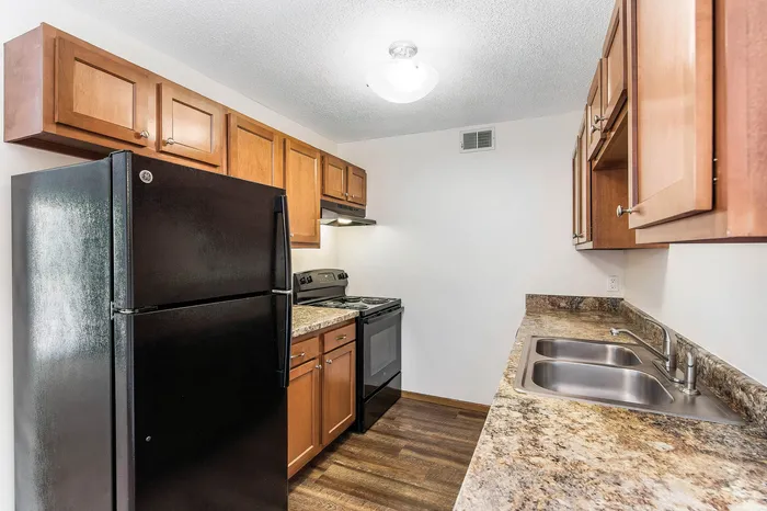 Inviting kitchen with sleek black appliances, elegant wood cabinetry, and stunning granite countertops.