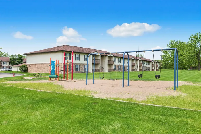 Charming apartment community featuring spacious green lawns and a vibrant playground for family enjoyment.