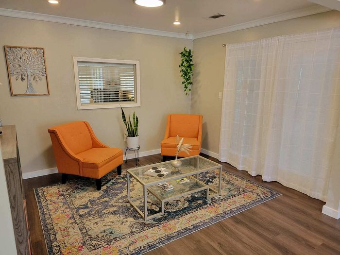 Inviting leasing office with cozy orange chairs, modern decor, and a colorful rug for a vibrant atmosphere.