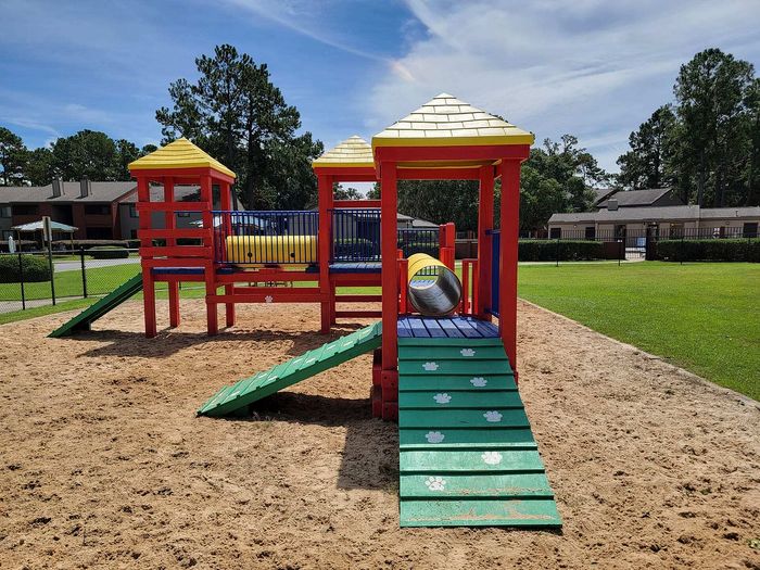 Vibrant playground with colorful slides and climbing structures surrounded by lush greenery, offering a perfect family-friendly environment.