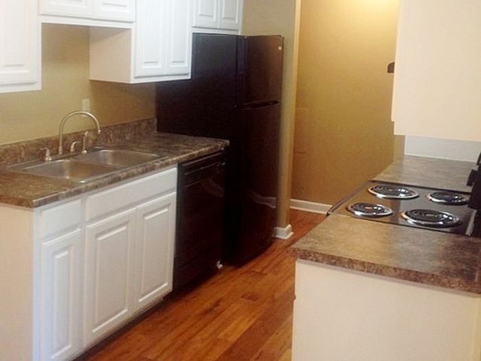 Charming kitchen with elegant countertops, sleek black appliances, and warm hardwood floors, offering a cozy culinary space.