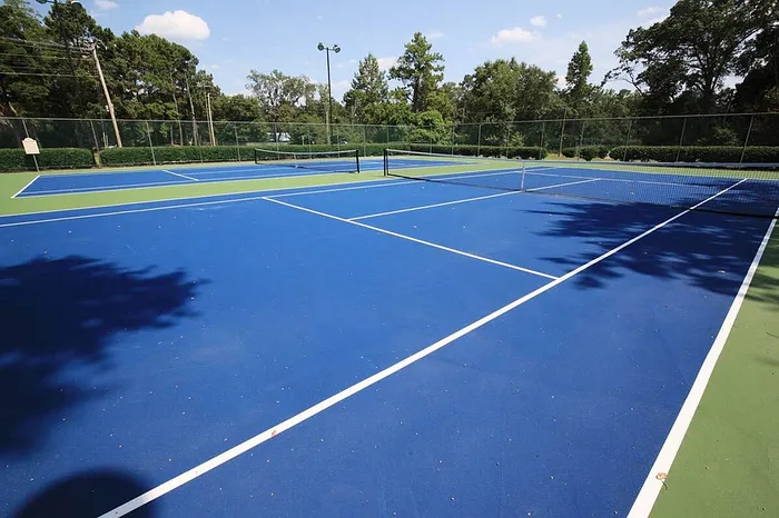 Vibrant outdoor tennis court surrounded by lush greenery, perfect for sports enthusiasts and leisure activities.
