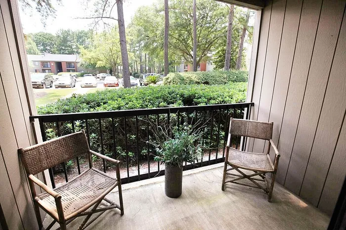 Charming balcony retreat with rustic wicker chairs and lush garden view, perfect for serene mornings and relaxing evenings.