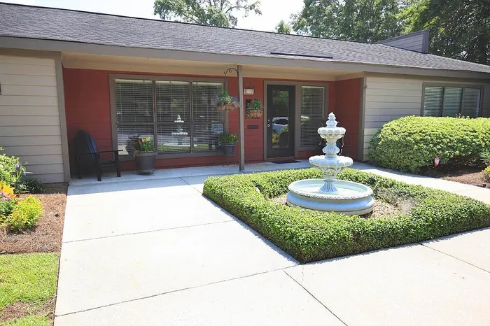 Charming residential entrance with a decorative fountain, lush greenery, and inviting architecture.