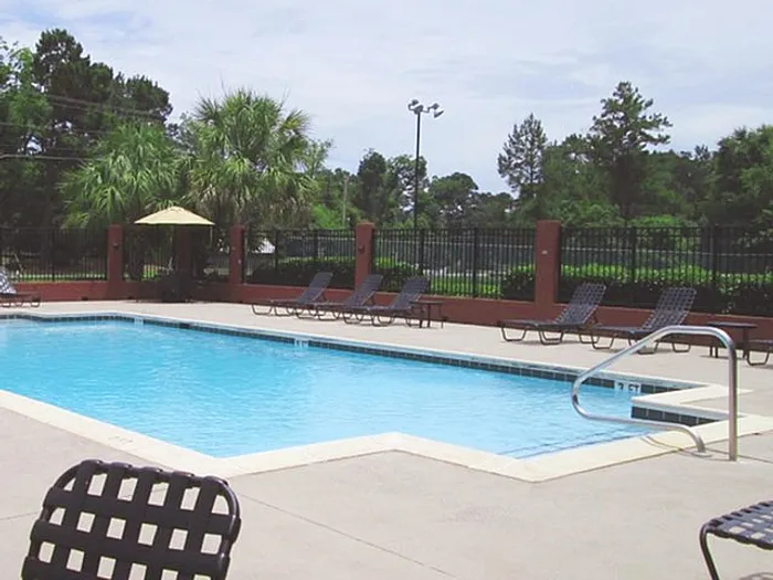 Inviting outdoor pool area with modern loungers and lush greenery, perfect for relaxation and sunshine.
