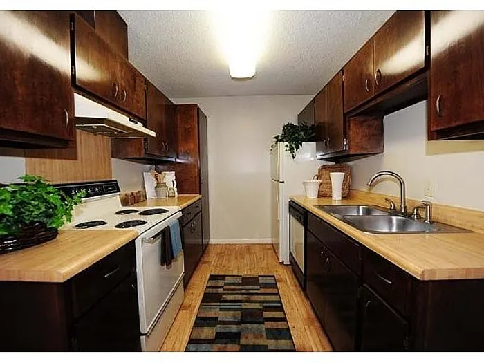 Charming galley kitchen with rich wooden cabinetry, sleek countertops, and ambient lighting, perfect for culinary enthusiasts.