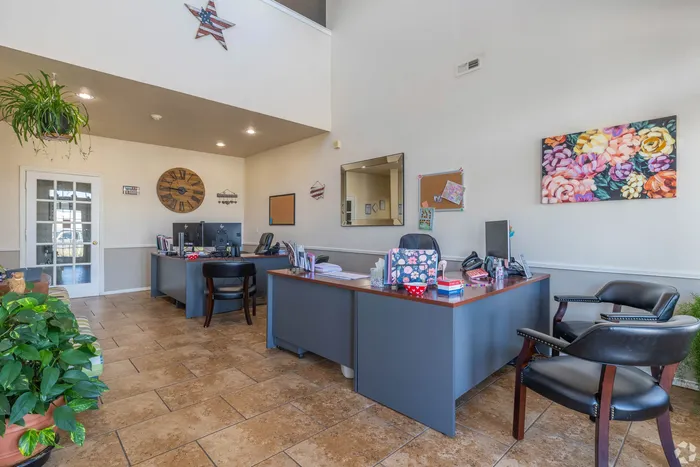 Inviting office space with stylish contemporary decor, featuring elegant wooden desks, vibrant floral artwork, and lush indoor plants.