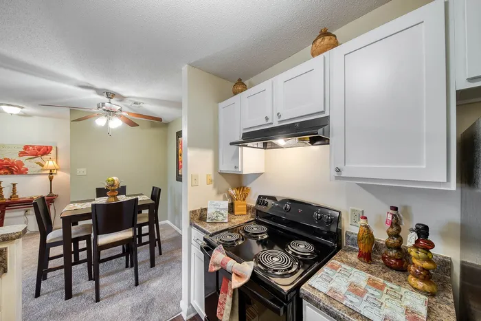 Charming kitchen and dining area featuring a modern stove, sleek cabinetry, and stylish decor with a cozy four-seater dining table under elegant lighting.