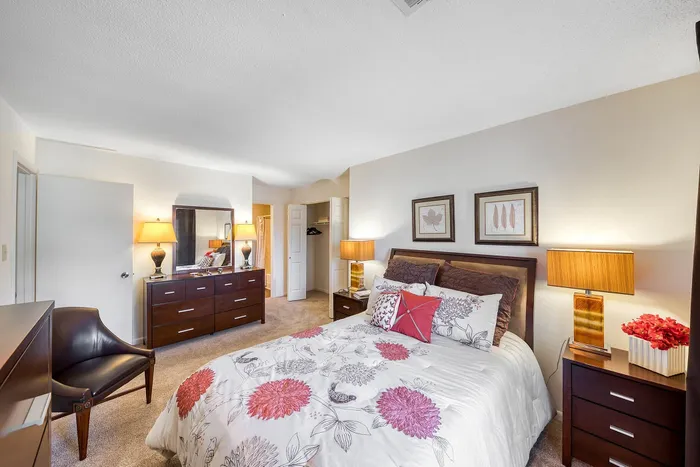 Elegant bedroom with stylish floral bedding, warm lighting, and modern furniture exuding a cozy and inviting atmosphere.