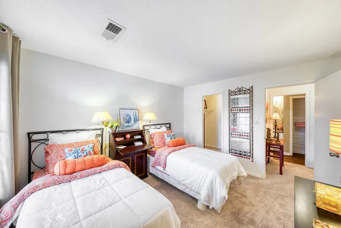 Bright twin bedroom with cozy decor, inviting warmth and comfort, featuring plush bedding, stylish lamps, and ample storage space.