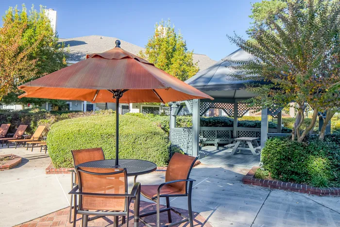 Charming outdoor space featuring a cozy seating area with umbrellas and a stylish gazebo surrounded by lush greenery.