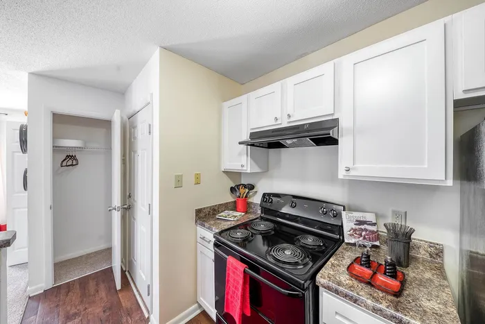 Modern kitchen with sleek black appliances, white cabinets, and stylish countertops, featuring wooden flooring.
