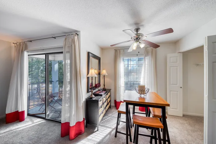 Inviting dining area with elegant table and chairs, enhanced by natural light and modern decor. Features sliding glass door leading to a serene balcony, perfect for enjoying the outdoors.