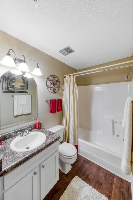 Elegant bathroom with modern fixtures, featuring a sleek countertop, mirror with lighting, and cozy decor accents.
