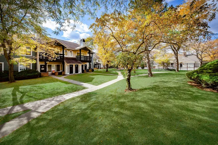 Charming apartment complex with lush green lawns and vibrant autumn foliage, offering serene and picturesque living surroundings.