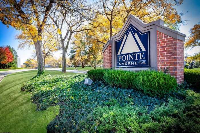 Charming neighborhood entrance sign surrounded by lush greenery and vibrant autumn trees, offering a warm welcome at Pointe Inverness.