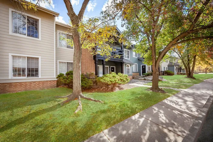 Charming suburban apartment complex surrounded by lush greenery and mature trees, offering a serene and inviting atmosphere.