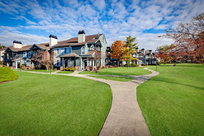 Charming townhouse community with vibrant autumn foliage and inviting pathways under a bright blue sky.