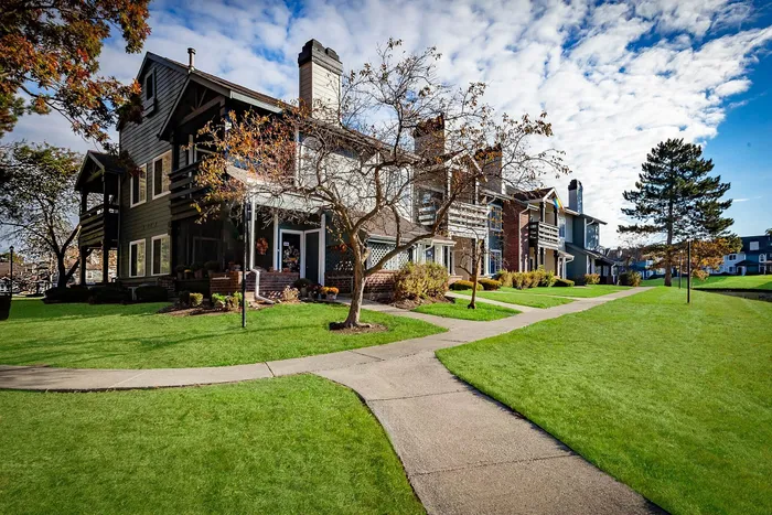 Charming apartment complex with rustic architecture, lush green lawns, and a serene suburban setting.