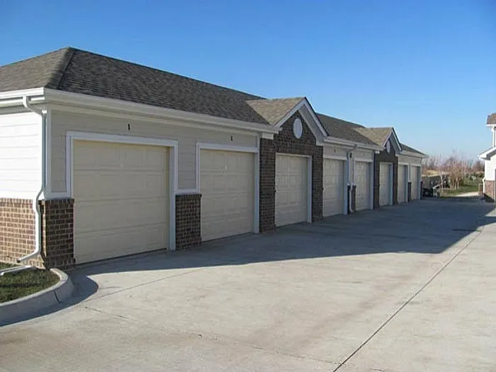 Charming row of residential garages with brick accents and white doors in a sunny suburban setting.