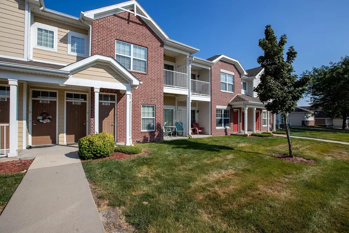 Charming residential complex featuring modern brick facades, private balconies, and lush green landscaping.