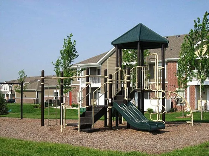 Charming community playground with modern play structures, nestled amidst stylish apartment buildings and lush greenery.