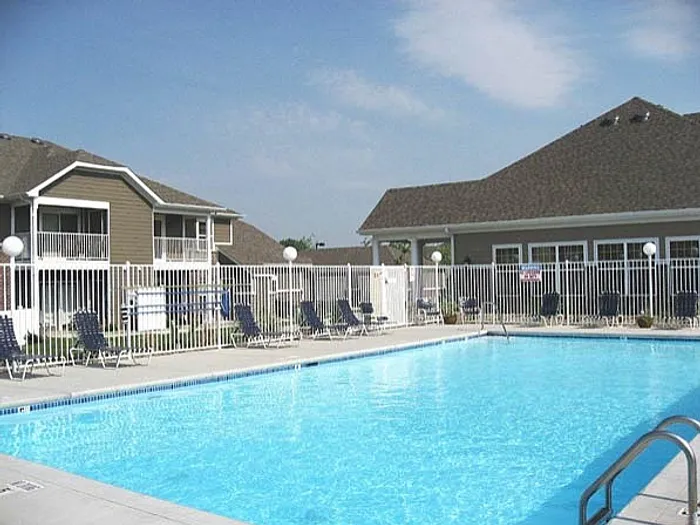 Inviting community pool with lounge chairs and modern apartment complex, perfect for relaxation and leisure.