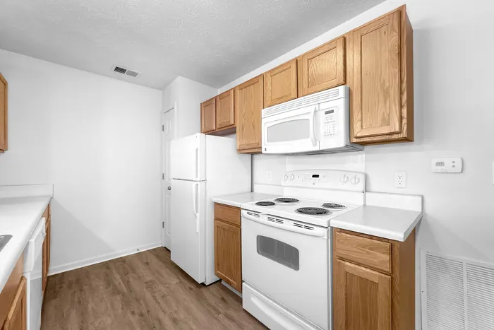 Modern kitchen with sleek wooden cabinets, white appliances, and elegant countertops, offering a sophisticated cooking space.