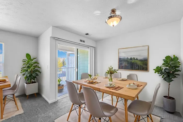 Bright and modern dining room with elegant decor and a sliding glass door leading to a sunny balcony.