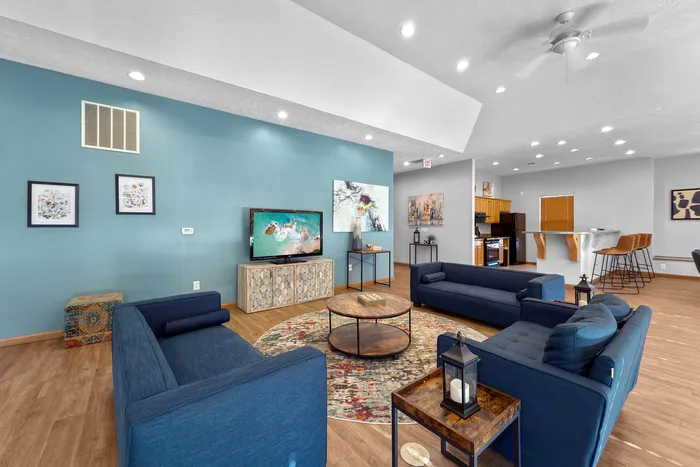 Inviting open living space with elegant blue sofas, artistic decor, and a modern kitchen bar area, perfect for relaxation and entertaining.