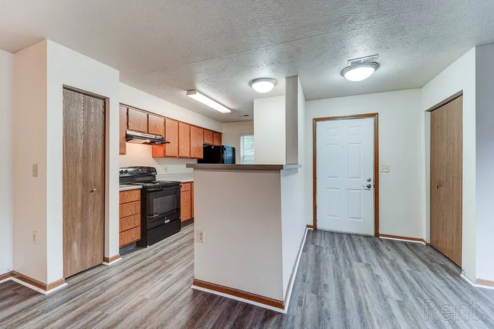 Inviting apartment interior showcasing a modern kitchen with wooden cabinetry, sleek appliances, and elegant flooring.