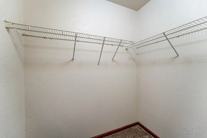 Spacious walk-in closet with sleek wire shelving and textured walls, perfect for organized storage.