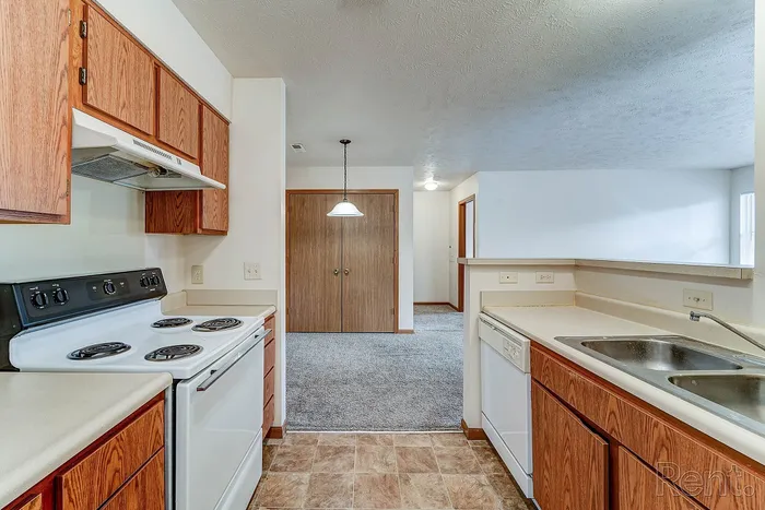 Charming kitchen with warm wood cabinetry, sleek appliances, and inviting open-concept design leading to a cozy living area.