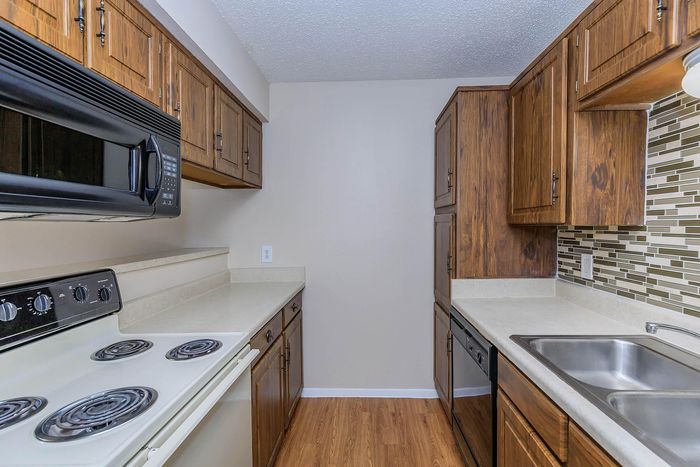 Inviting galley kitchen with elegant wooden cabinetry, modern appliances, and a chic tile backsplash, perfect for culinary creativity.