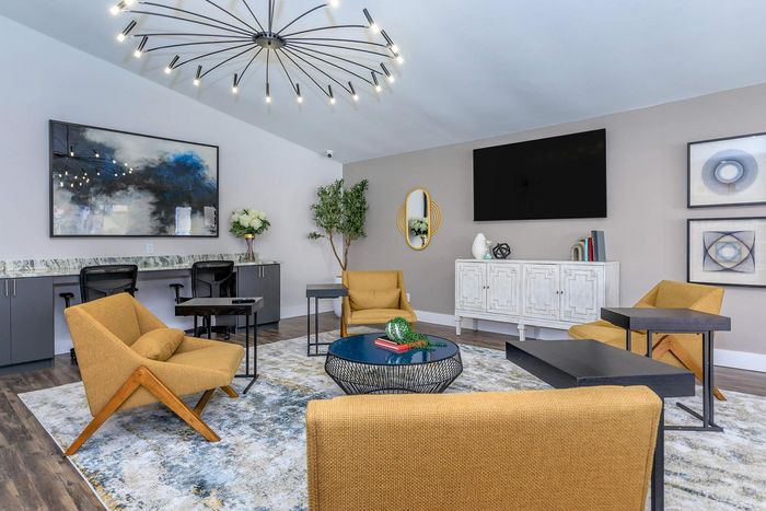 Luxurious living room with modern d&eacute;cor, featuring stylish mustard armchairs, a chic chandelier, and elegant artwork. Perfect for relaxation and gatherings.