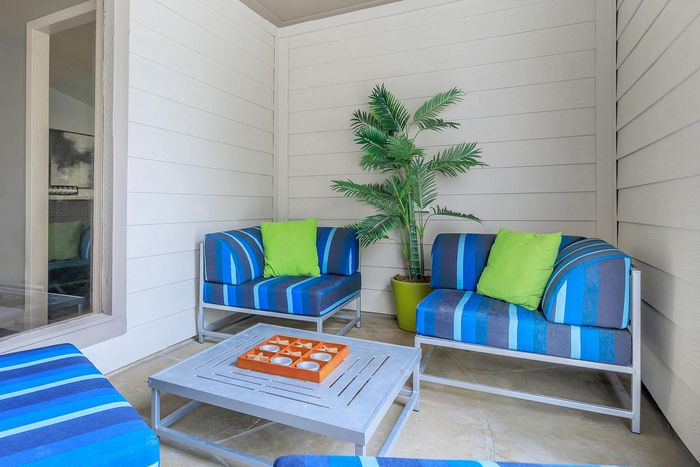 Chic outdoor patio with vibrant blue and green striped seating, complemented by a stylish modern coffee table and lush potted plant.