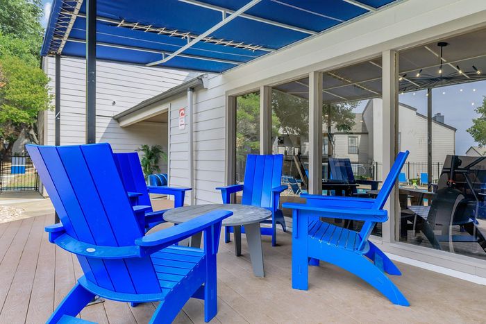 Charming outdoor patio featuring vibrant blue Adirondack chairs under a modern canopy, perfect for relaxation and social gatherings.