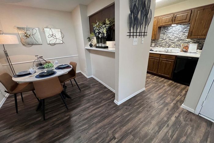 Cozy dining area with modern decor and an elegant view into a stylish kitchen featuring sleek wooden cabinetry and contemporary backsplash.