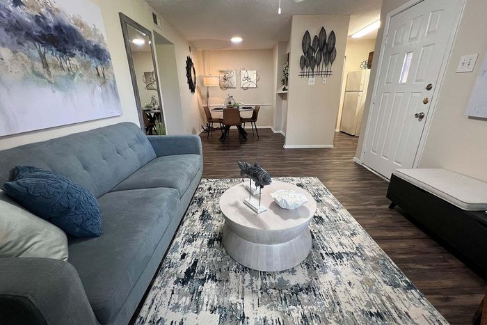 Inviting living room showcasing a cozy blue sofa, stylish abstract art, and elegant dining area with chic decor.