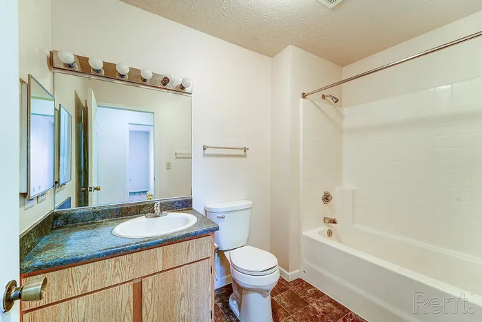 Bright, modern bathroom featuring a spacious mirror, elegant vanity, and pristine bathtub.