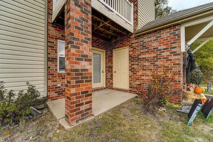 Charming brick apartment exterior with inviting front entrance and cozy patio space, perfect for enjoying outdoor relaxation.